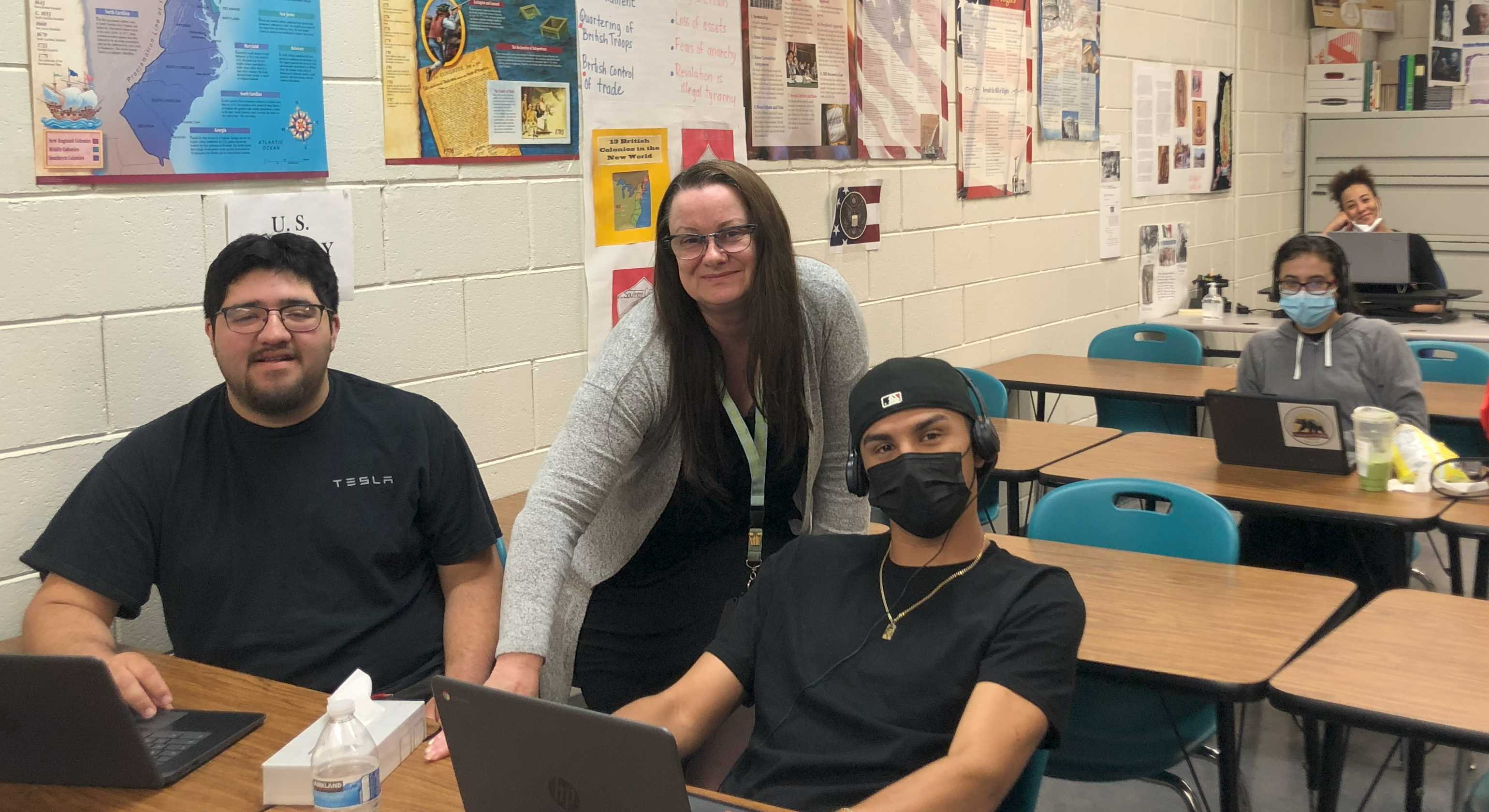 Student in HSD classroom working on laptops with teacher assistance. 
